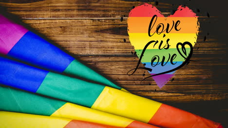 animation of love is love text and rainbow flag over wood table background