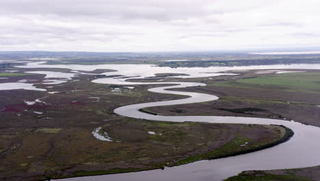 aerial over winding river and wetlands of national importance