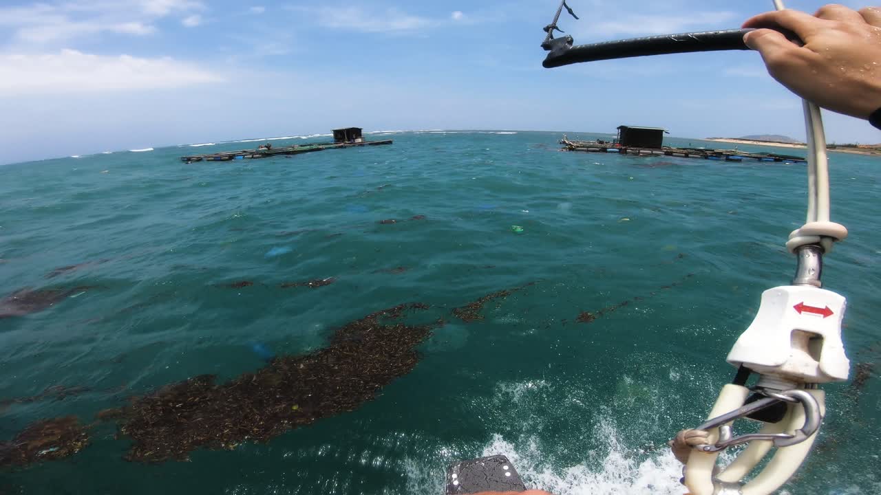 Kitesurfing in trash polluted sea in Vietnam floating fishing farms, pov
