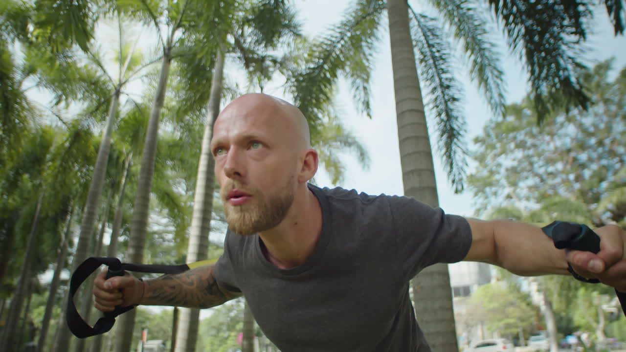 Strong Man Exercising with Suspension Straps in Park
