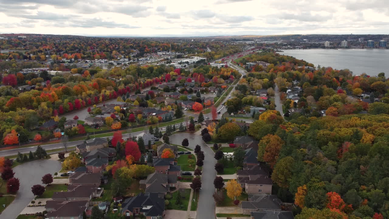 vista aérea del paisaje sobre una ciudad suburbana rodeada de coloridos árboles otoñales, con follaje amarillo rojo y naranja