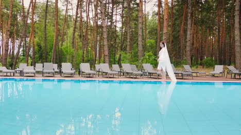 the bride with a long veil is walking around the pool wedding in a luxury hotel slow motion video