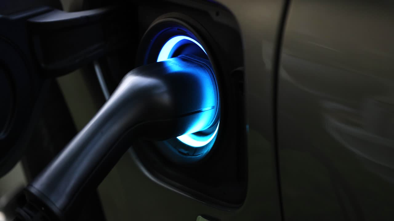 Araç şarj konektöründe yeşil-mavi yanıp sönen elektrikli şarj cihazı 4K video.