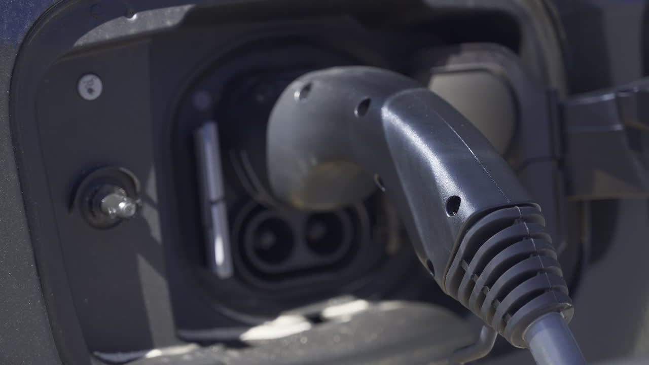 Close up of an electric car charger plugged into a black car