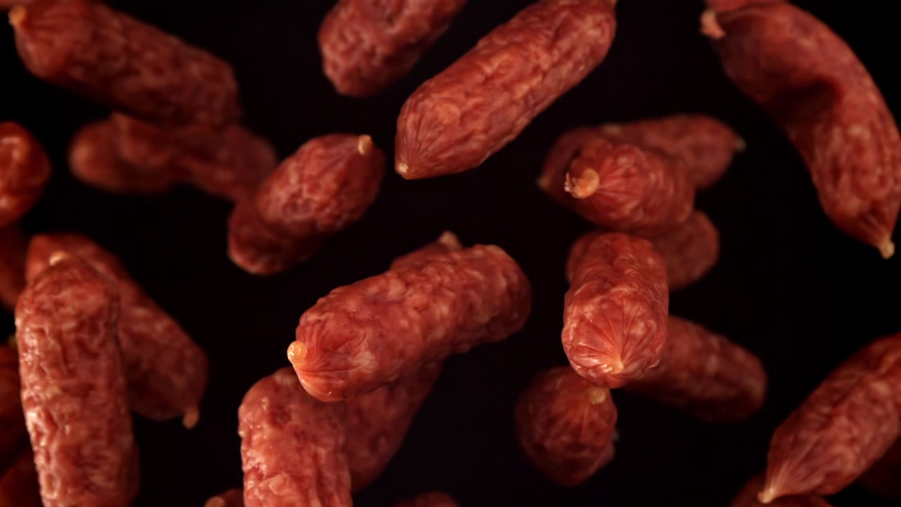 Zbliżenie mini salami spadającego w zwolnionym tempie na czarnym tle.