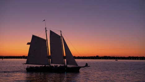 sailing ship, hudson river shot, from a boat, statue of liberty at dusk, teal and orange sky