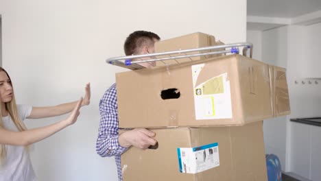 unrecognizable man standing with luggage in cardboard boxes while moving in with girlfriend