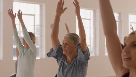 yoga class healthy old woman practicing warrior pose enjoying group workout in fitness studio