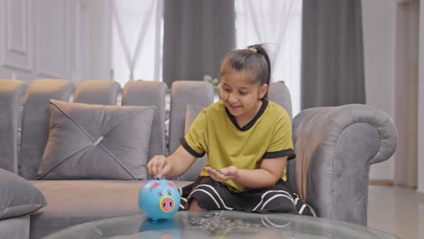 una niña india feliz contando dinero de su alcancía