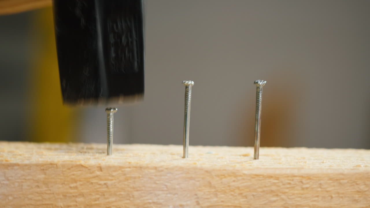 Hammer Driving Nails into a Wooden Board
