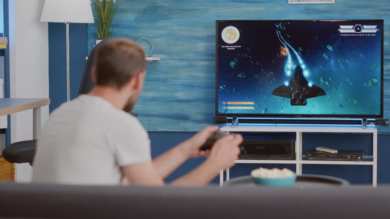 Uomo seduto sul divano che gioca a un videogioco sparatutto in prima persona su una TV con un controller wireless in mano