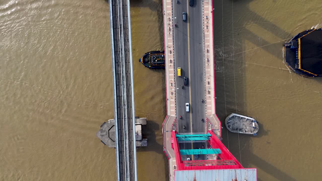 Drone aerial top view of a busy bridge crossing a wide river with cars motorcycles train and tugboats of coal minning in Palembang Indonesia Asia