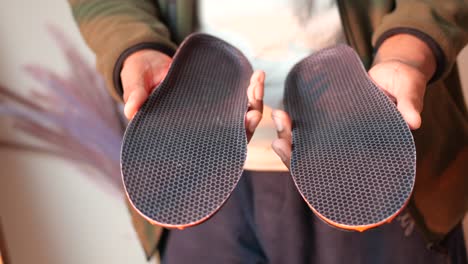 person holding a pair of comfort shoe insoles