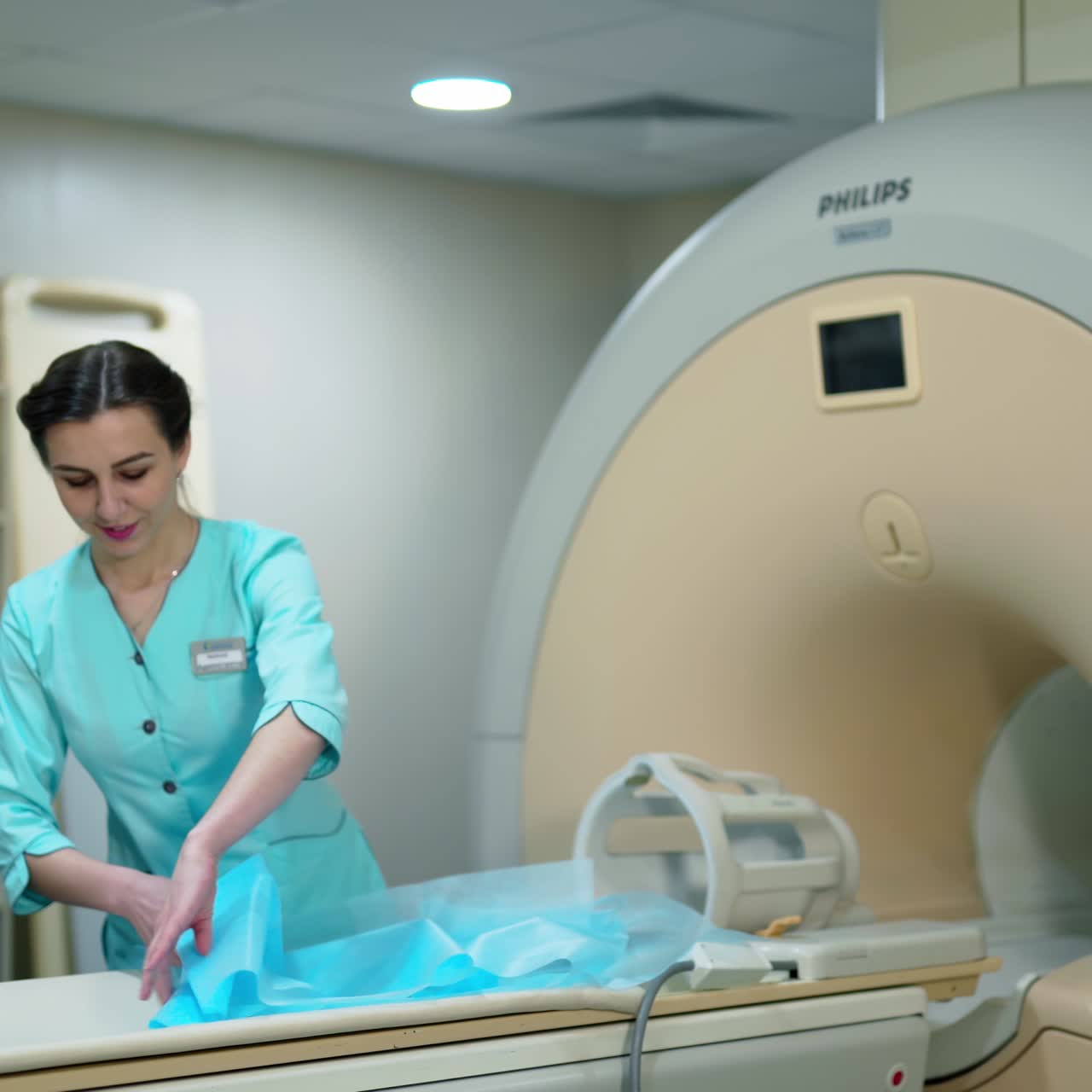 Nurse near magnetic resonance imaging diagnostic machine. Female doctor is standing by the modern MRI scanner in clinic. Computerized innovation tomography for medical tests.