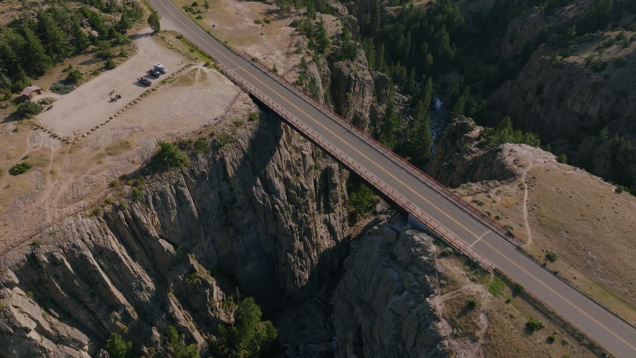 Aerial tilt up over Sunlight Creek Bridge, showing the dramatic canyon drop and expansive wilderness views in Wyoming