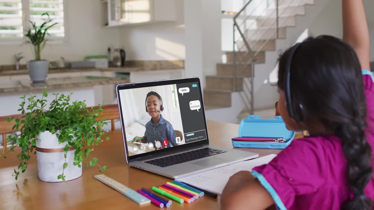 Schoolgirl using laptop for online lesson at home, with her school friend and web chat on screen