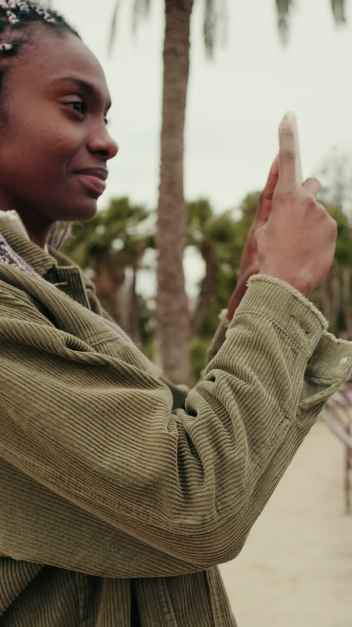 Giovane donna afroamericana che scatta una foto con lo smartphone nel parco