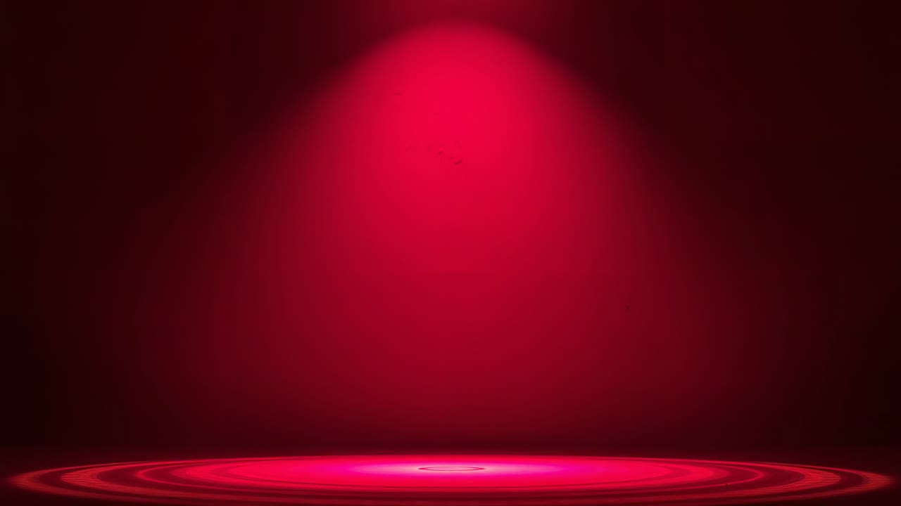 Widening overhead spotlight forming concentric rings and bright disk on center stage, red backdrop