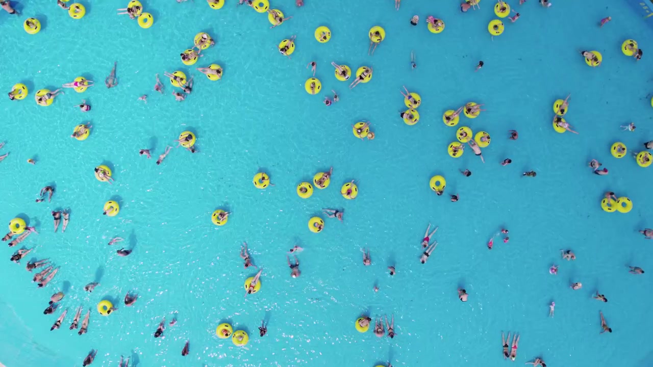 Aerial View of People Floating on Yellow Tubes in a Swimming Pool