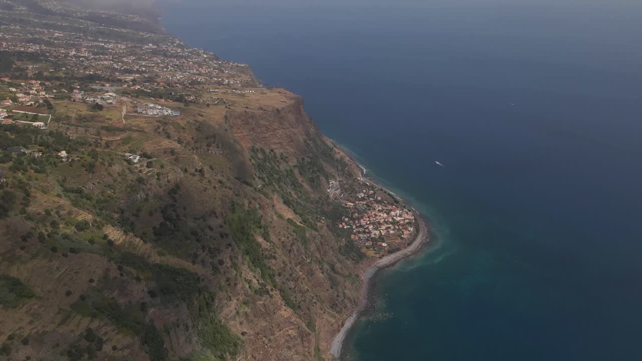 Aerial view of the Calheta parish in the Madeira Island, flying above the coast showing the contrast between the village near the sea and the rest of the houses on top of the mountain