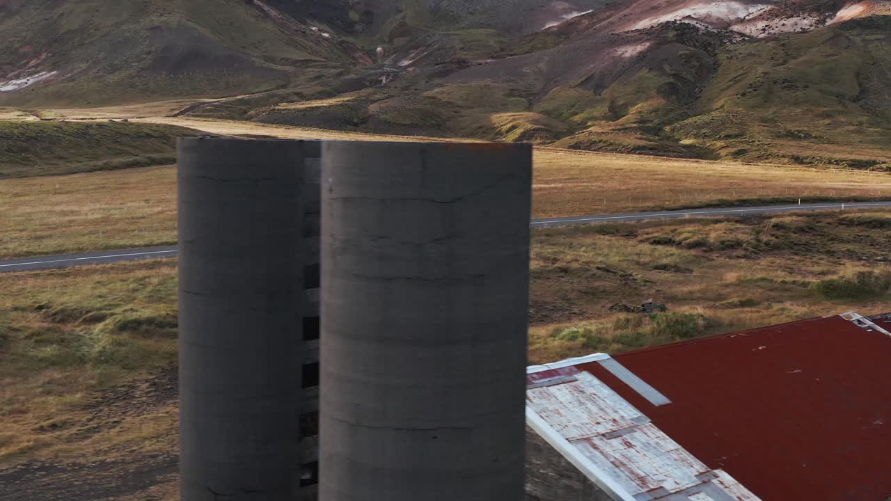 edificio roto abandonado con silos de grano en el valle islandés, camión blanco pasando en segundo plano, antena