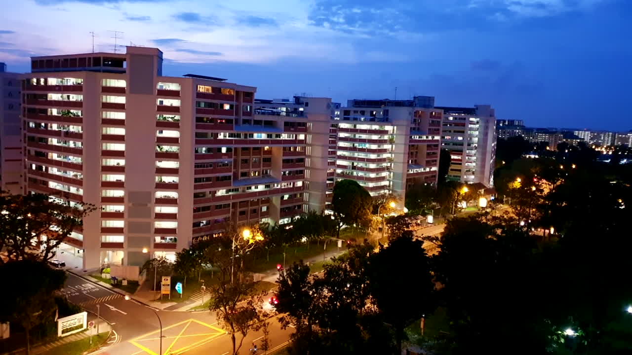 tomada del crepúsculo de un tranquilo y moderno barrio de apartamentos de la ciudad en singapur con coches que pasan ocasionalmente