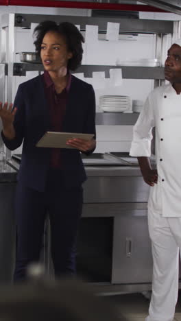 gerente femenina afroamericana usando una tableta y hablando con chefs