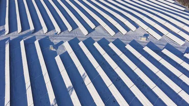 Aerial view of snow-covered solar panels in a serene winter landscape