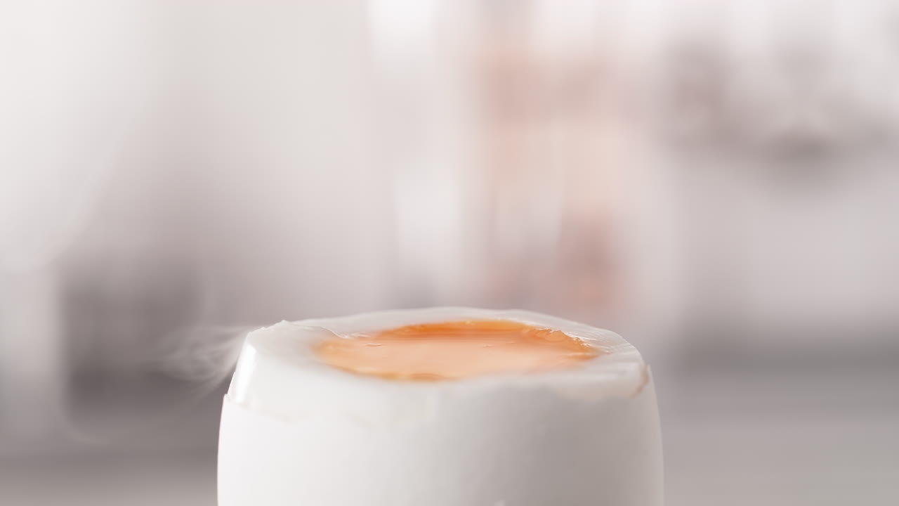 Strø salt på et varmt, dampende bløtkokt egg i et skall i sakte film og makro