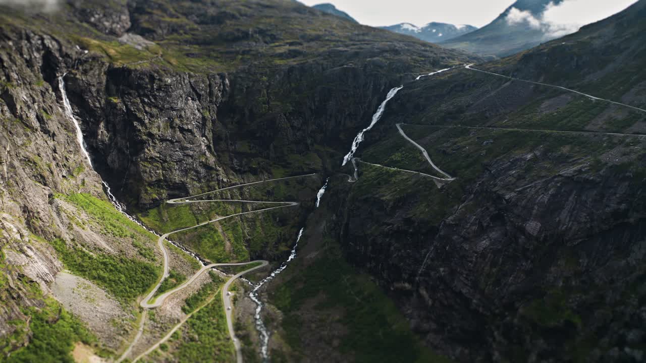 트롤스티겐의 유명한 헤어핀 곡선은 노르웨이 산맥의 가파른 절벽에 맞춰 폭포를 둘러싸고 휘어져 있습니다.