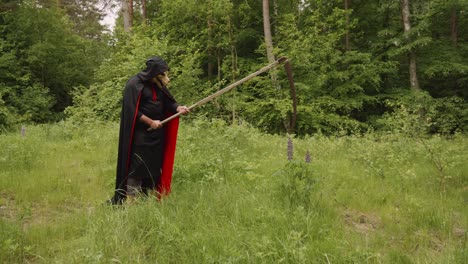 Portrait-Of-Creepy-Reaper-With-Animal-Skull-Head-And-A-Scythe-Standing-In-The-Wilderness