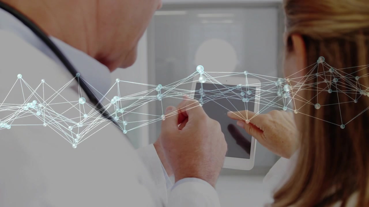 Médico sénior sosteniendo una tableta mientras un colega toca la pantalla activando una red animada que muestra datos de salud.