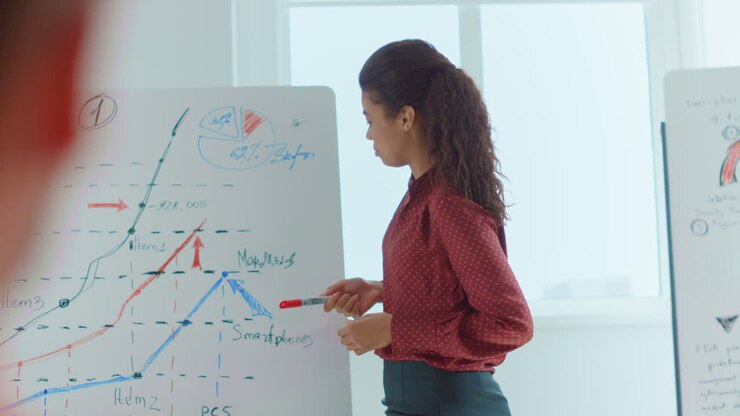 African woman training employees office. Speaker pointing hand white board