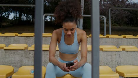 mujer usando el teléfono en las gradas del estadio