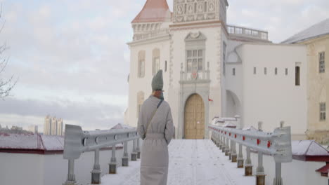 mujer caminando a través de un puente nevado a un castillo en invierno