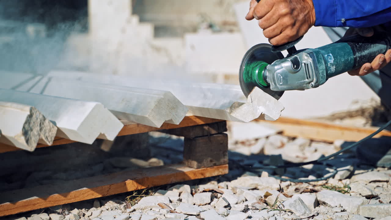 Worker cutting stone block. Worker with a small angle grinder cuts a granite