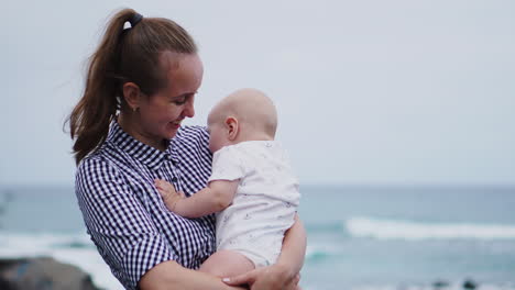 against the serene sea and beach setting, a heartwarming portrait depicts a mother's kiss on her daughter's cheek. the vacationing family radiates happiness, as the mom lovingly embraces her toddler