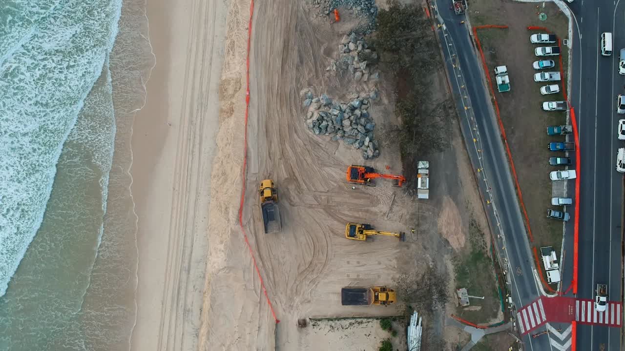 grandes maquinaria de construcción utilizada para reparar las dunas de arena de la playa dañadas por la reciente oleada de un ciclón tropical