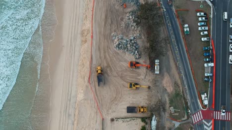 large construction machinery used to repair beach sand dunes damaged by recent swell from a tropical cyclone