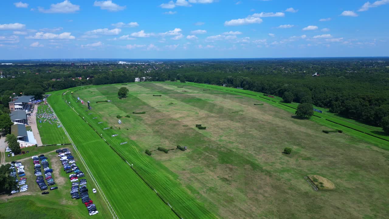 horse racing track with spectators enjoying the competition on a sunny summer day. Great aerial view flight ascending drone