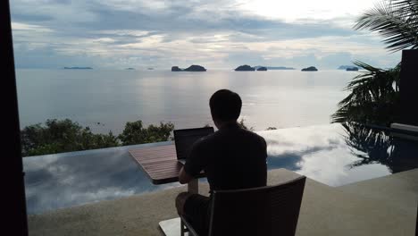 asian man working on the laptop by the pool - back view-1