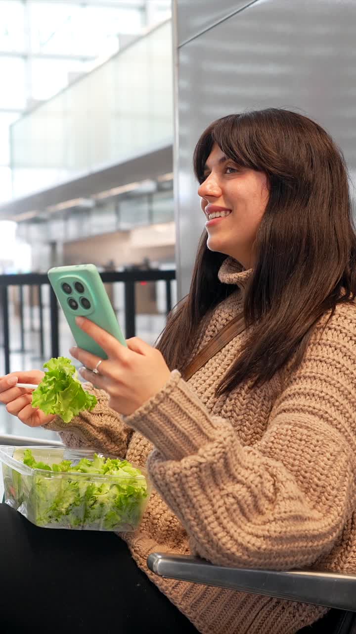 Young Woman Eating Salad and Using Smartphone in Public Space