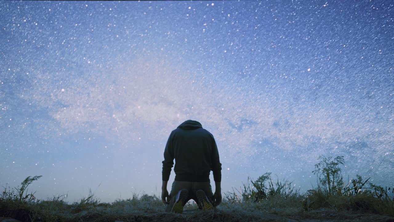 Man Kneeling and Praying Under a Starry Sky