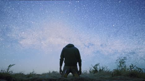 man kneeling and praying under a starry sky