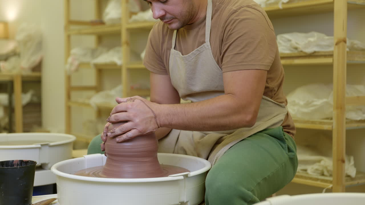 Potter shaping clay spinning on pottery wheel in studio small business workshop