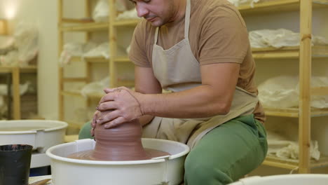 potter shaping clay spinning on pottery wheel in studio small business workshop