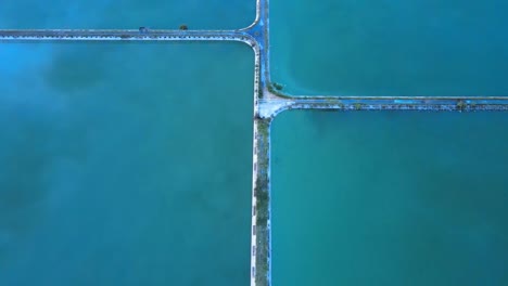 imágenes aéreas siguiendo un camino sobre un lago de piscicultura que refleja el cielo en su superficie