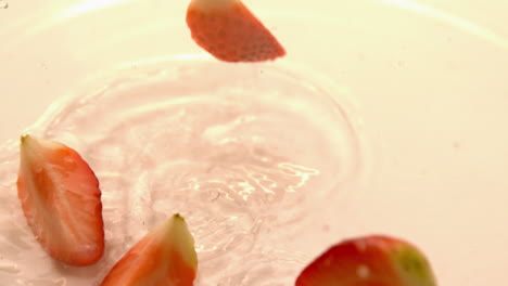 Strawberry-pieces-falling-on-white-wet-surface