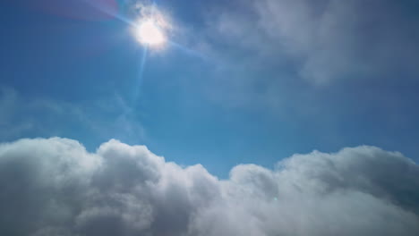 sun shinning above cloudscape, view from plane cabin