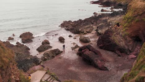 drone view of unrecognizable traveler standing on rocky seashore